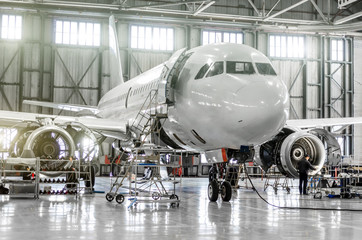 passenger aircraft on maintenance of engine and fuselage repair in airport hangar.