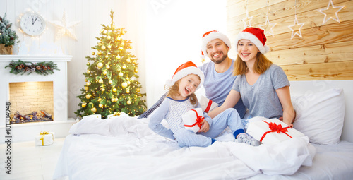 Plakat szczęśliwa rodzina matka ojciec i dziecko w Boże Narodzenie rano w łóżku