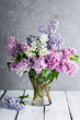 lilac branches in a glass vase on a gray background
