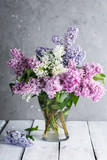 Fototapeta  - lilac branches in a glass vase on a gray background