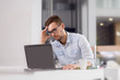 © Goran - Pensive businessman reading something from laptop at office.