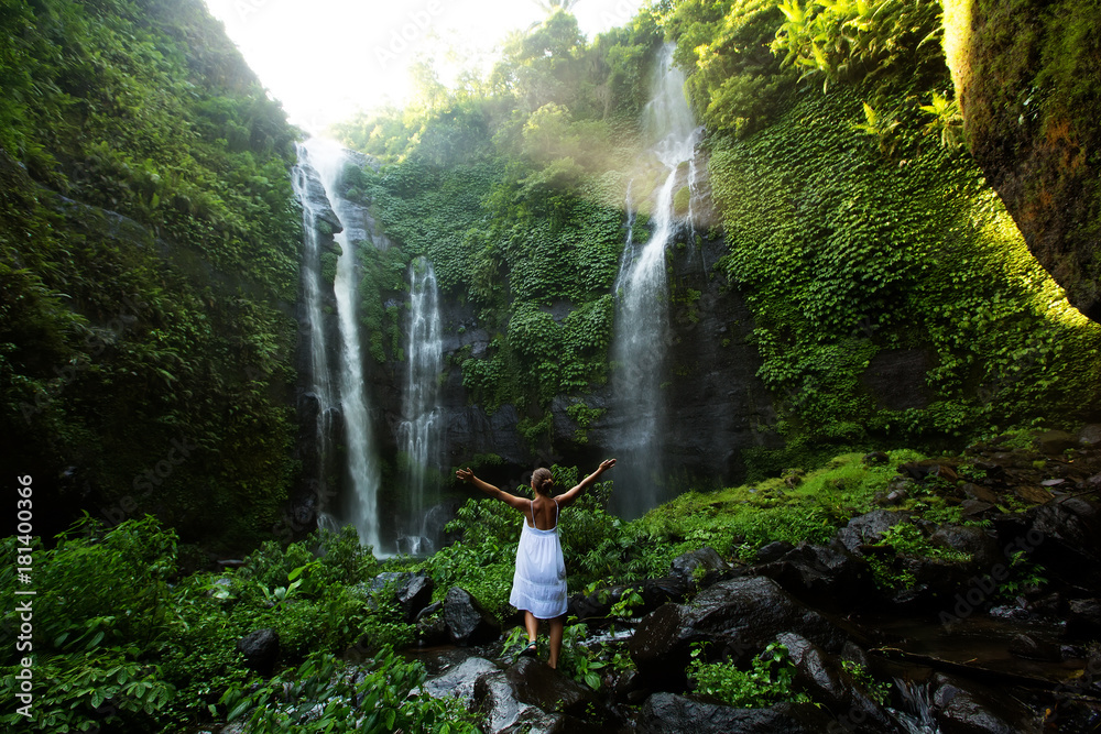 Woman in white dress at the Sekumpul waterfalls in jungles on Bali ...