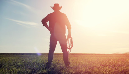 a man cowboy hat and a loso in the field. american farmer in a f