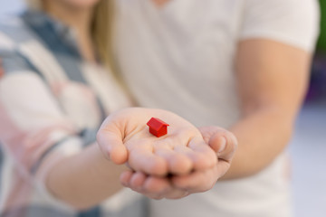 couple showing small red house in hands