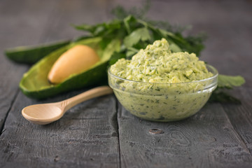 Cream puree avocado with parsley, dill and garlic in a bowl on a rustic table. The dish is vegetarian diet.