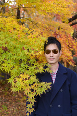 Wall Mural - Japanese man with maple leaves in autumn background