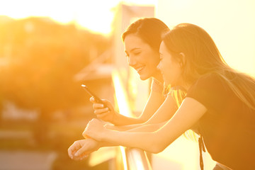 Poster - Two friends using a smart phone at sunset