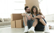 married couple sitting near cardboard boxes in a new apartment