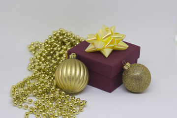 Gift box with an yellow bow and two golden balls, shiny yellow beads on the table