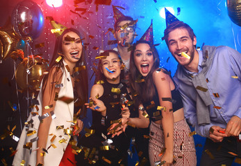 Cheerful young people showered with confetti on a club party.