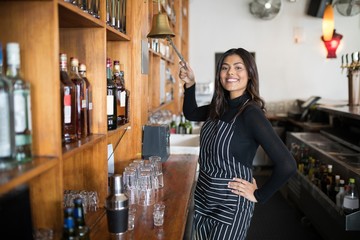 Wall Mural - Smiling waitress ringing bell at counter