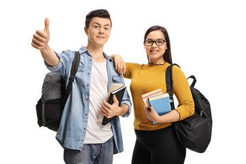 Cheerful teenage students with backpack and books making a thumb up sign