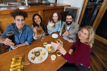 Wall Mural - Happy friends showing glass of drinks in bar