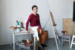 Female artist in her spacious white studio working with watercolor painting.  Natural lighting. Disclosure of creativity concept. Horizontal composition.
