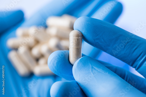 Photographie Scientist hands in gloves hold pills, new pill research concept