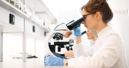 Young scientist looking through microscope in laboratory