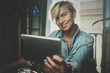 © SFIO CRACHO - Smiling young woman wearing casual clothes and using electronic device while spending relax time home livingroom.Attractive woman owner communicating on digital tablet.Blurred background.