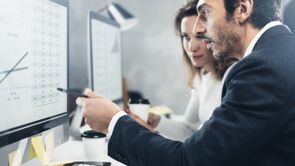 Two business person at working process at office.Young professionals work with new market project on desktop computers. Blurred background.Horizontal.Cropped.