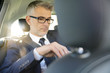© goodluz - Businessman sitting in car backseat working on digital tablet
