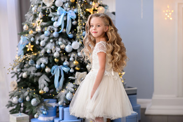 merry christmas celebration. beautiful little girl in a amazing dress sitting near the christmas tre