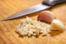 Finely Cut Garlic Over Wooden Cutting Board