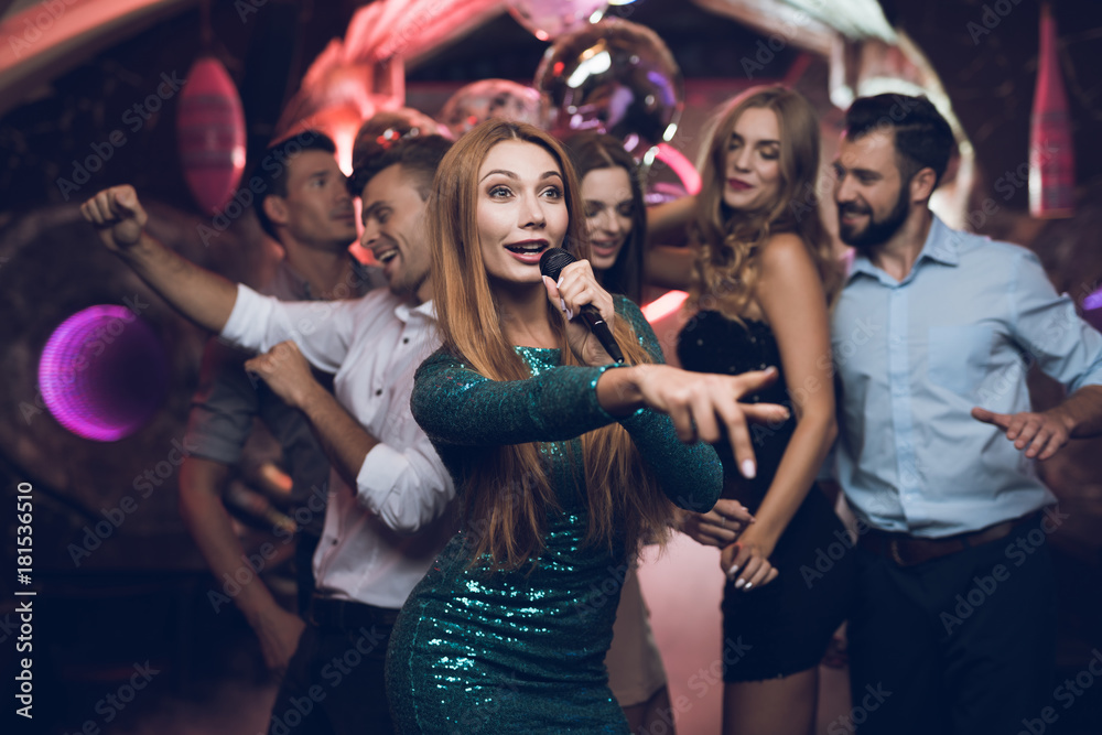 green green dress karaoke A woman in a is singing songs with her friends at a club. Her friends have fun on the background. Stock Photo compare-at-set