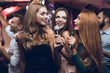 © VadimGuzhva - Three beautiful girls sing in a karaoke club. Behind them are men waiting for their turn.