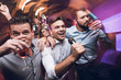 © VadimGuzhva - Three men sing at a karaoke club. Young people have fun in a nightclub. They are very cheerful and they smile.