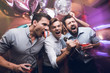 © VadimGuzhva - Three men sing at a karaoke club. Young people have fun in a nightclub. They are very cheerful and they smile.