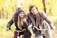 Happy Couple On Bikes In Forest During Fall Time