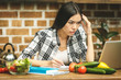 © denis_vermenko - Young beautiful asian stressed woman with laptop on kitchen. Working home. In stress. Freelance