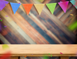 Leinwandbilder - colorful flag banner bunting and confetti on wood table at diagonal wooden wall,Leave space for display or montage of your design, Holiday new year concept.