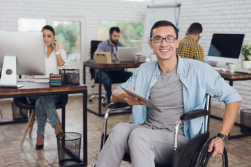 Disabled person in the wheelchair works in the office.