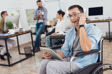 Wall Mural - Disabled person in the wheelchair works in the office. He talks on smartphone.