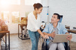 © VadimGuzhva - A girl gives a man in a wheelchair to sign documents in a paper tablet.