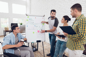 Wall Mural - Office workers and man in a wheelchair discussing business moments while working in a modern office.