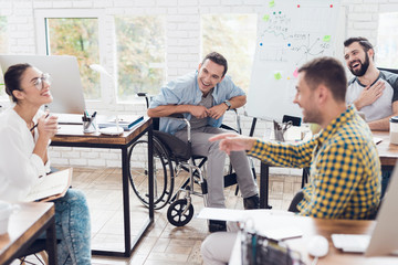 Wall Mural - Office workers and man in a wheelchair discussing business moments in a modern office.