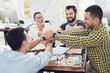 © VadimGuzhva - A group of young people discussing something in the office. They are showing a teamwork.