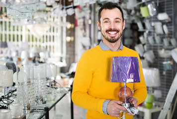 man in lighter shop choosing stylish and modern lamp for house interior