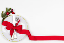 Christmas Table Place Setting With Plate, Cutlery, Pine Branches,  Ribbon And Red Berries. Winter Holidays And Festive Background. Christmas Eve Dinner, New Year Food Lunch. View From Above, Top