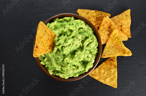 Fotografía Bowl with guacamole and nachos on the background of a slate board