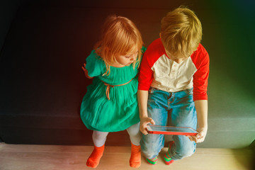 Wall Mural - little boy and girl looking at touch pad at home