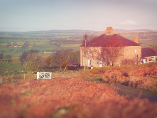 Wall Mural - A large stone house in the middle of English countryside at sunset on a winters day.