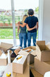 © David Pereiras - Embraced couple looking through the window of their new house