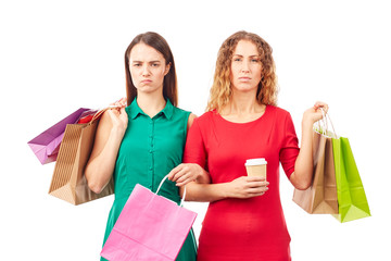 portrait of two female friends holding multi-colored shopping bags