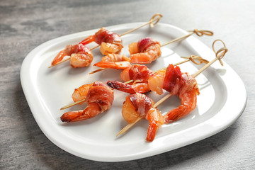 Wall Mural - Plate with skewered shrimps wrapped in bacon on table