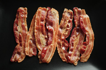 Wall Mural - Cooked bacon rashers on plate, closeup