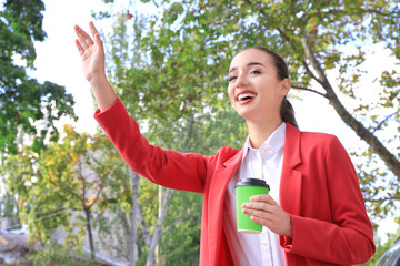 Wall Mural - Young woman trying to catch taxi on city street