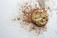 Single Chocolate Chip Cookie On A White Marble Table With Cocoa Powder