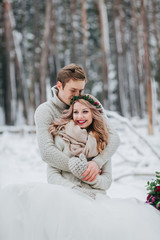 Wall Mural - Happy newlyweds are hugging in the winter forest. Couple in love. Winter wedding ceremony.